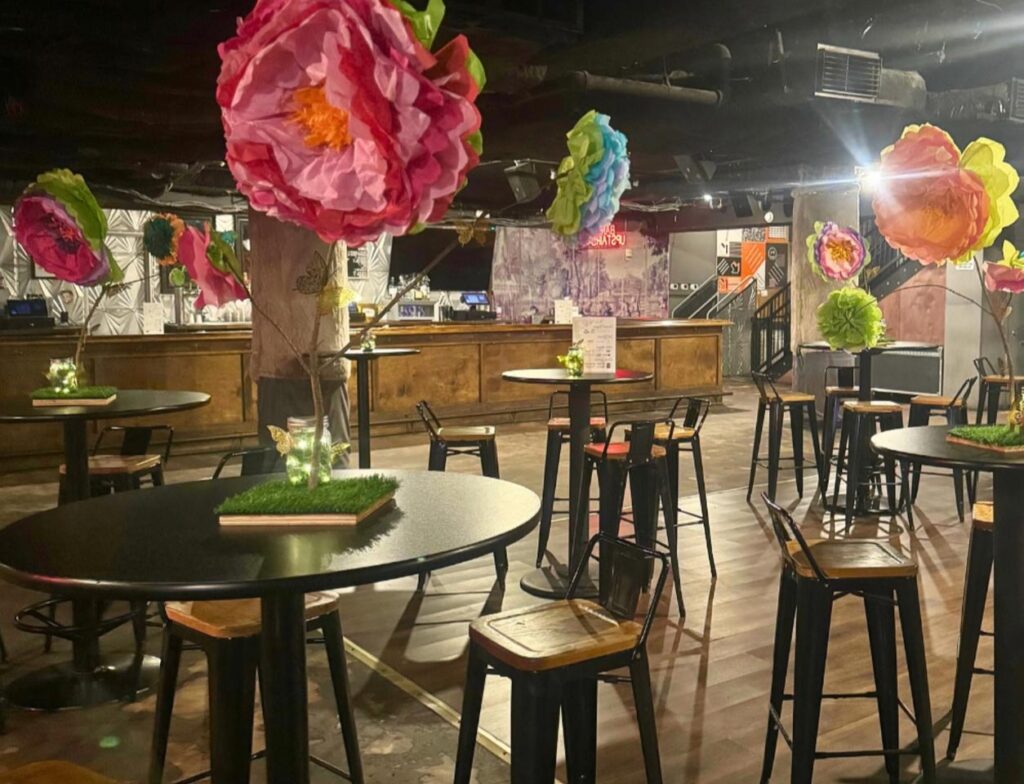 A cozy café interior with oversized colorful paper flowers decorating the space, creating a vibrant and inviting atmosphere